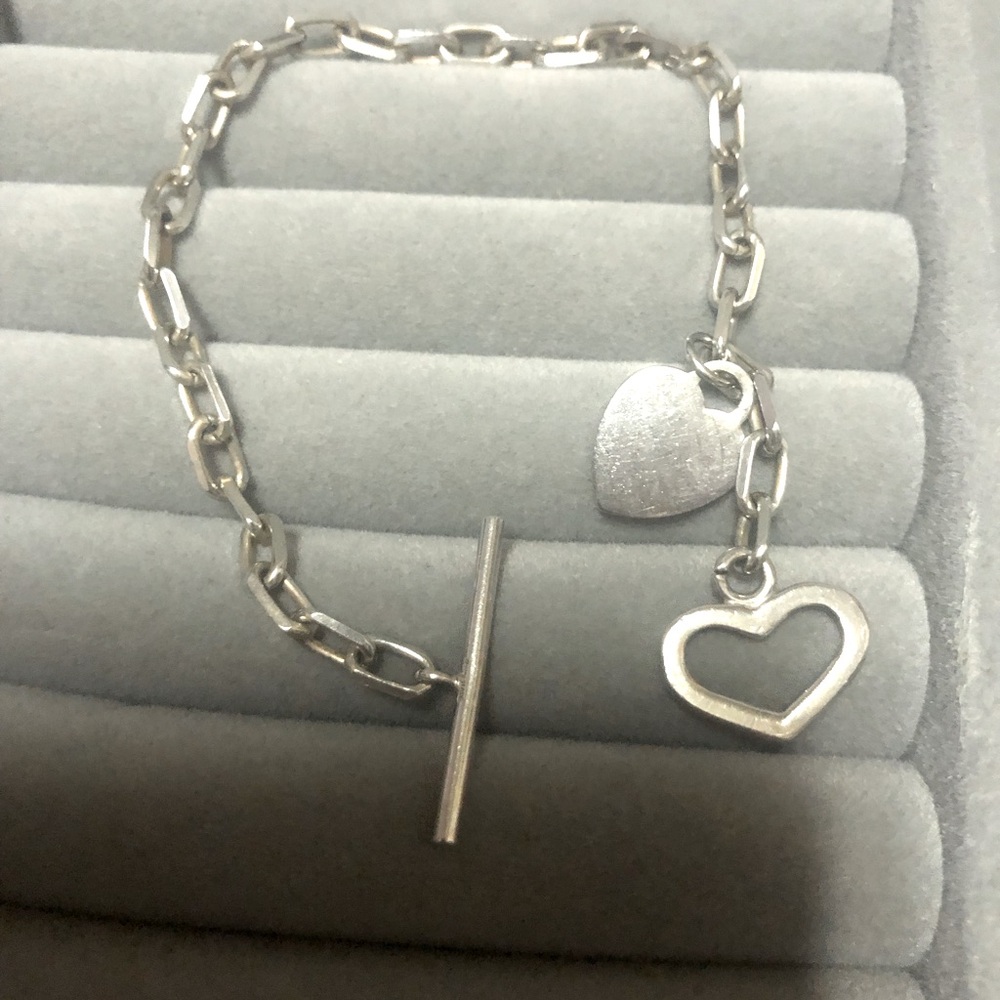 Silver bracelet with two heart shaped pendants. Pre owned in good condition.